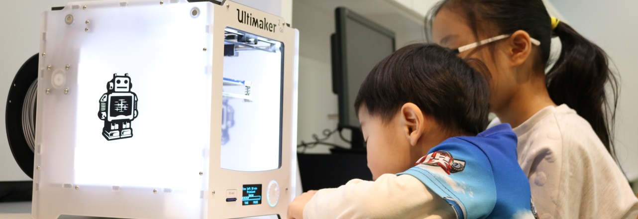 Young boy and girl watching a 3D printer